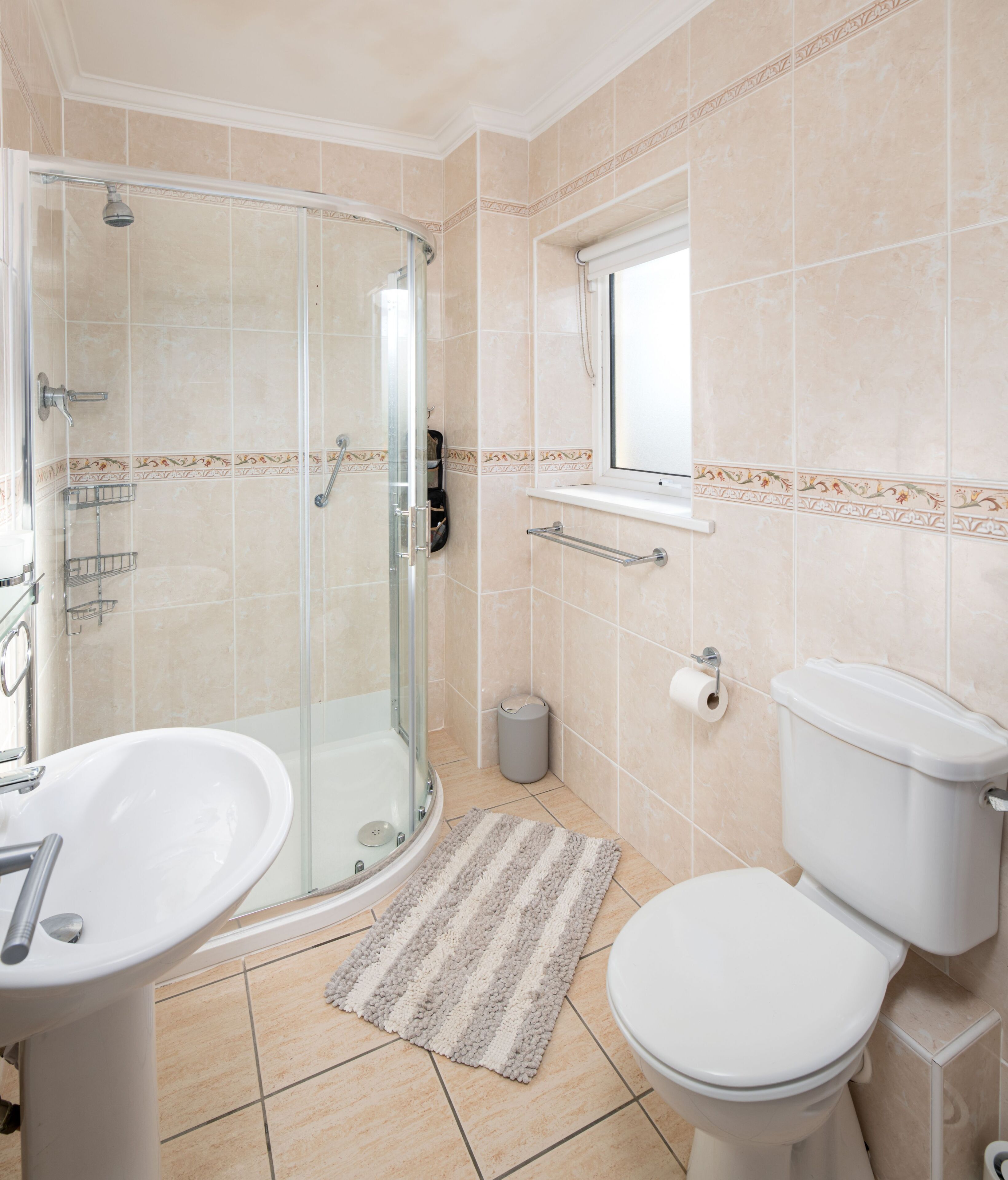 Une salle de bain avec une douche à parois de verre, un lavabo, des toilettes et une fenêtre.