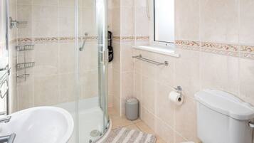 Une salle de bain avec une douche à parois de verre, un lavabo, des toilettes et une fenêtre.