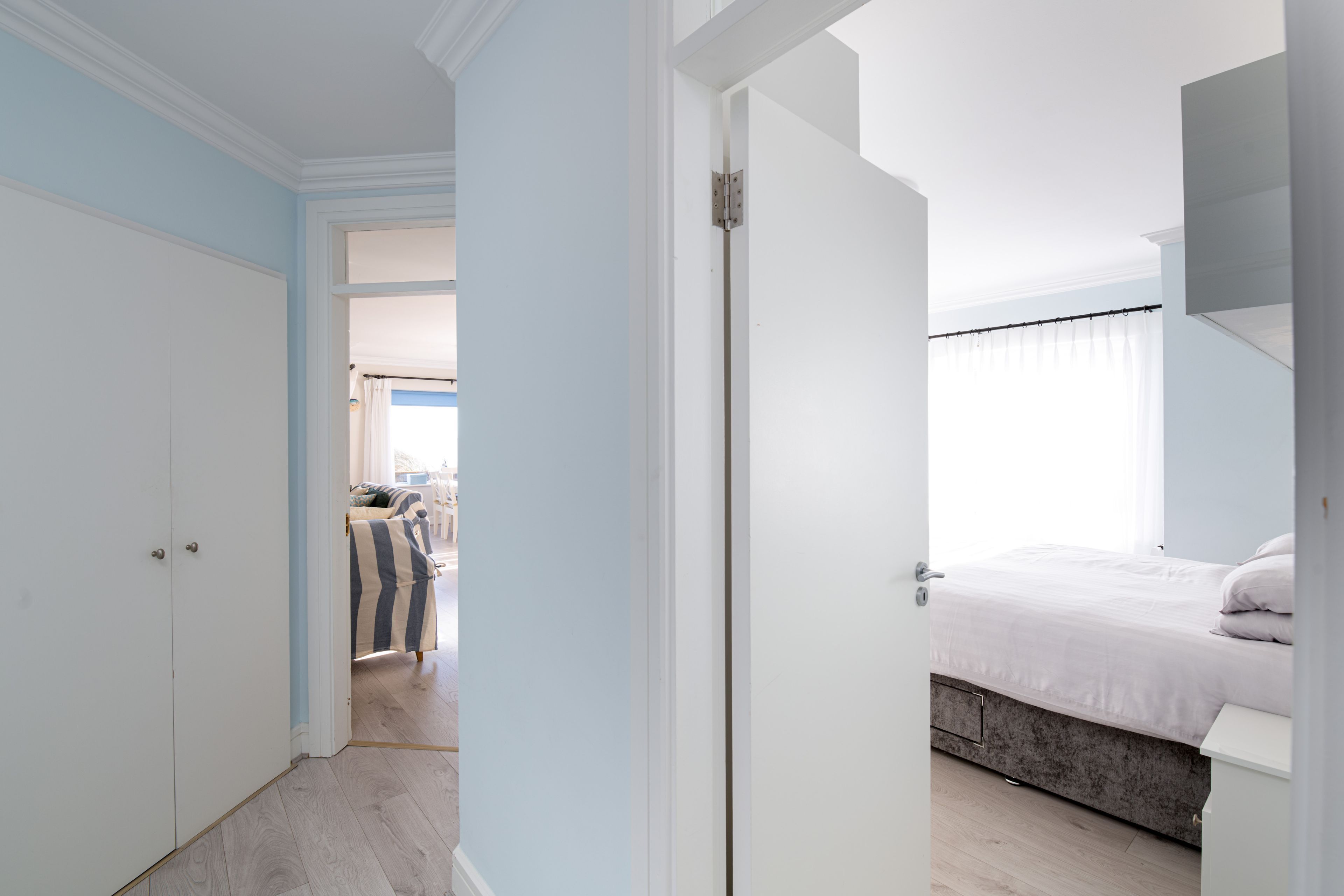 A bedroom with a bed, a wardrobe, and a door leading to another room.