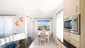 A modern kitchen with a dining area, featuring a large window, a microwave, and a bowl on the counter. - Seaview Apartment, Silversands, Rosslare Strand, Co. Wexford (Rosslare STrand)