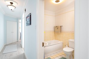 A bathroom with a bathtub, toilet, and a shower area. - Seaview Apartment, Silversands, Rosslare Strand, Co. Wexford (Rosslare STrand)