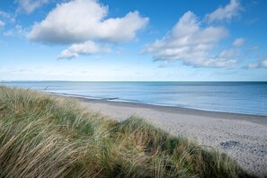 A beach with sand and grass in the foreground, and a clear blue sky with clouds in the background. - Seaview Apartment, Silversands, Rosslare Strand, Co. Wexford (Rosslare STrand)