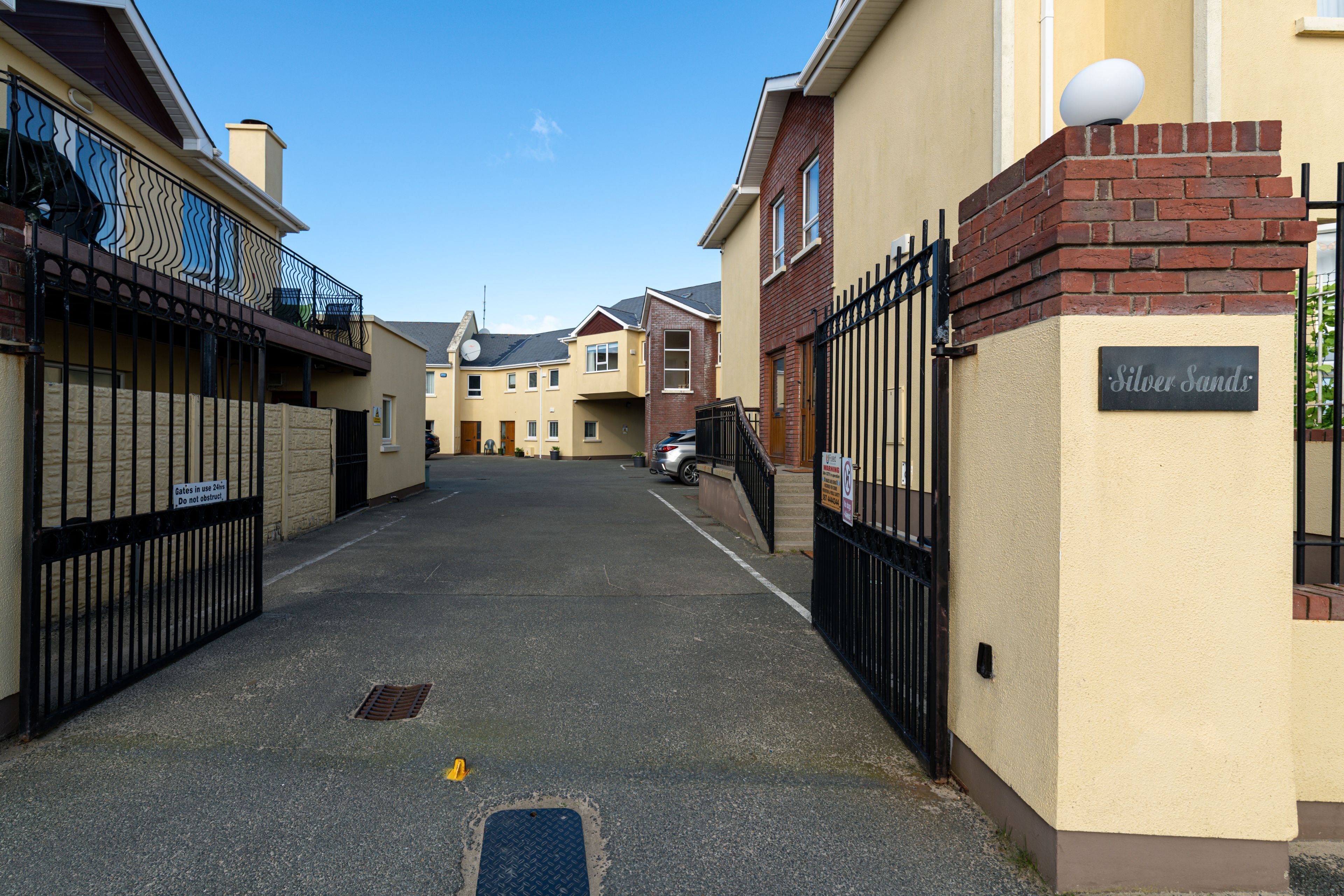 A residential street with houses, a gated entrance, and a sign reading "Silver Sands".