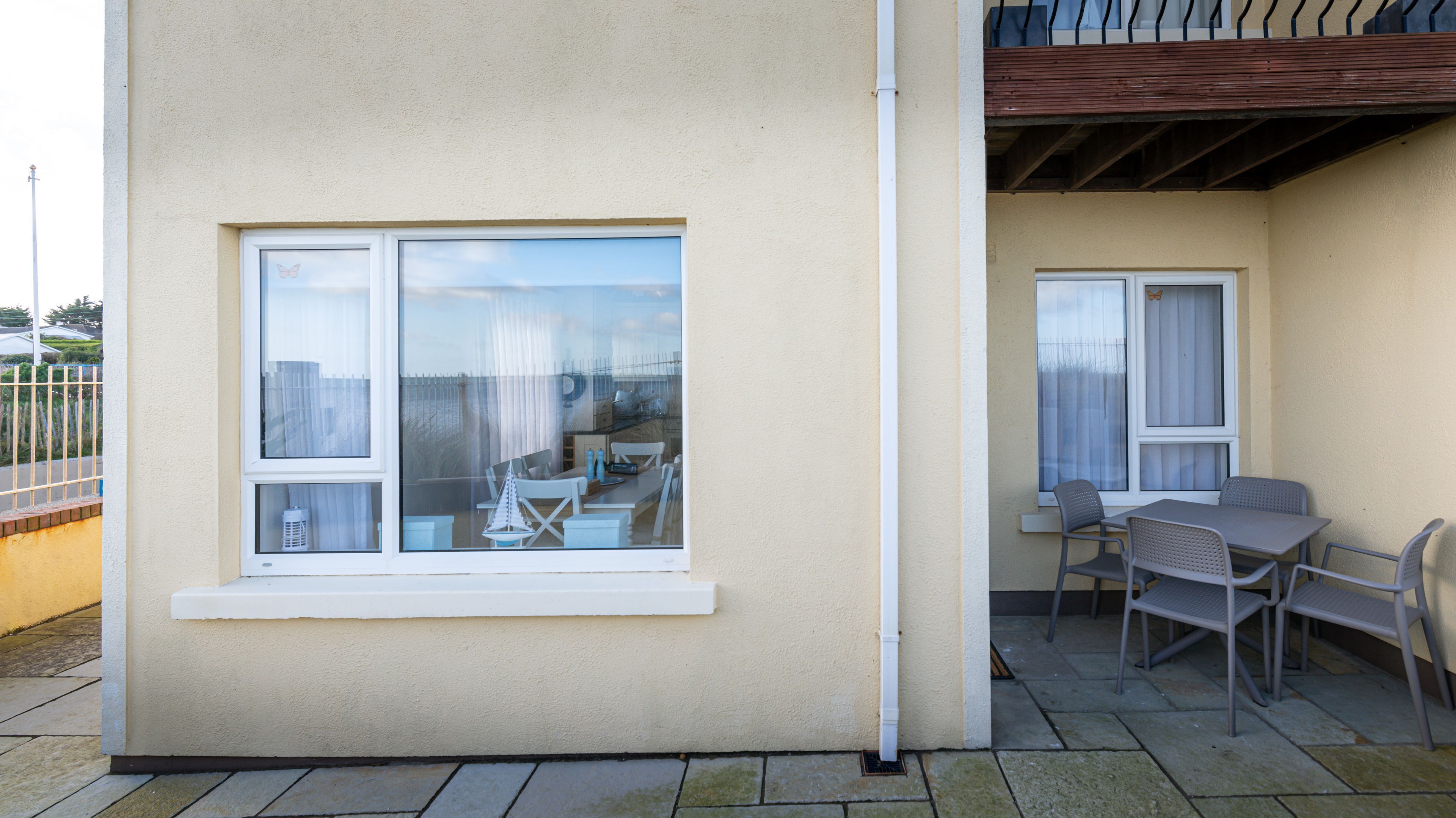 A building with a large window and a balcony with a table and chairs.