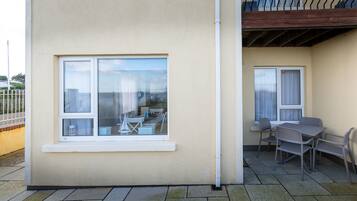 A building with a large window and a balcony with a table and chairs.