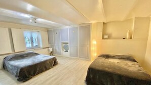 Une chambre avec deux lits, une fenêtre avec des rideaux, une lampe et une étagère avec divers objets.