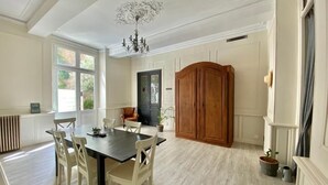 Un coin repas avec une table en bois foncé et des chaises blanches, un buffet en bois et un lustre.