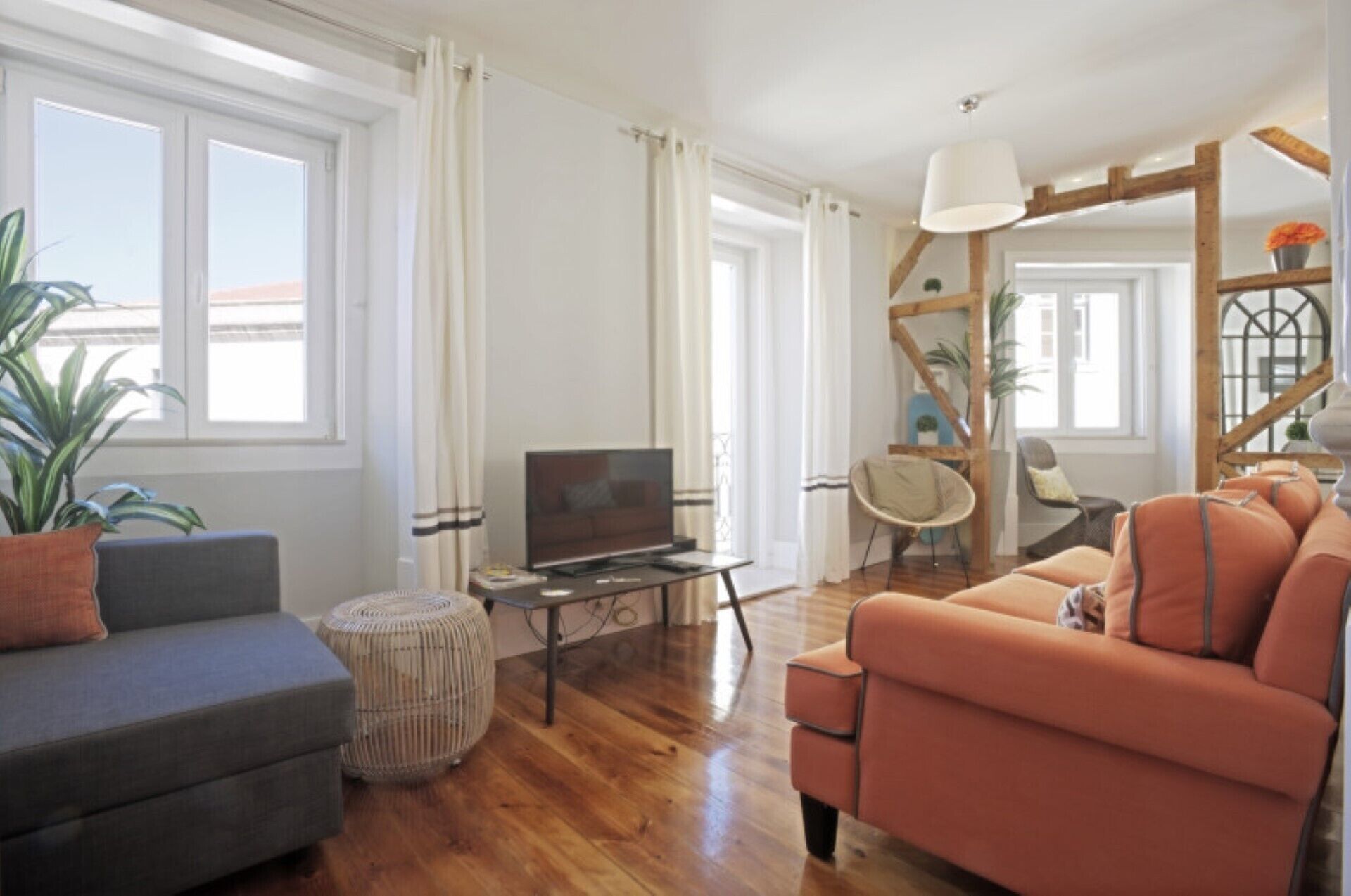 A modern living room with a sofa, ottoman, and a TV on a stand.
