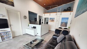 A modern living room with a leather sofa, a glass coffee table, and a flat-screen TV. - Attic apartment, Strandstr., side view. Sea view, 150 m to the Baltic Sea, renovated in 2025 (Kühlungsborn)