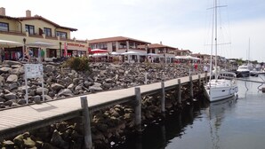 A marina with a wooden walkway, boats, and buildings with outdoor seating. - Attic apartment, Strandstr., side view. Sea view, 150 m to the Baltic Sea, renovated in 2025 (Kühlungsborn)