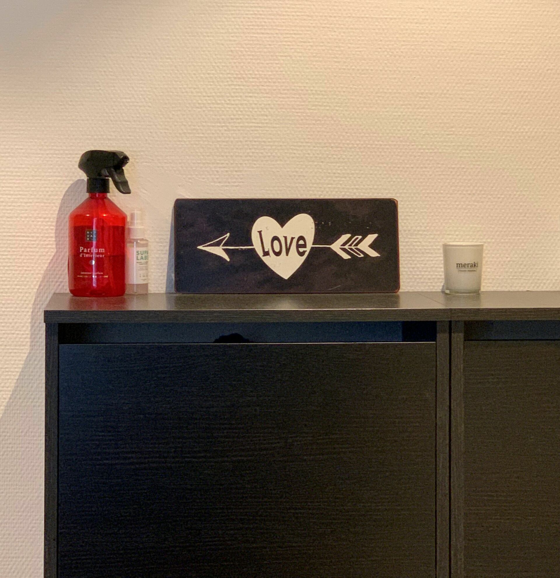 A black cabinet with a heart-shaped sign that reads "Love" and two arrows pointing in opposite directions.