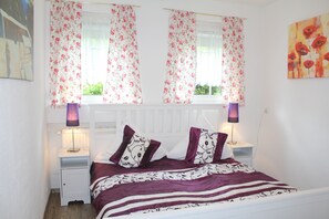 A bedroom with a bed, nightstands, and a window with floral curtains. - Large, beautiful holiday home in Daun with 14 sleeping possibilities, 3 bathrooms, WiFi (Daun)