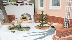 A garden with a small pond, rocks, and a tree.