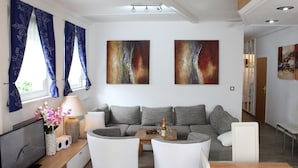 A modern living room with a grey sofa, a wooden coffee table, and a TV on a wooden stand.