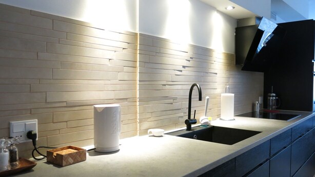 A modern kitchen with a sleek black faucet, a built-in sink, and a countertop with a wooden tray and a white container.