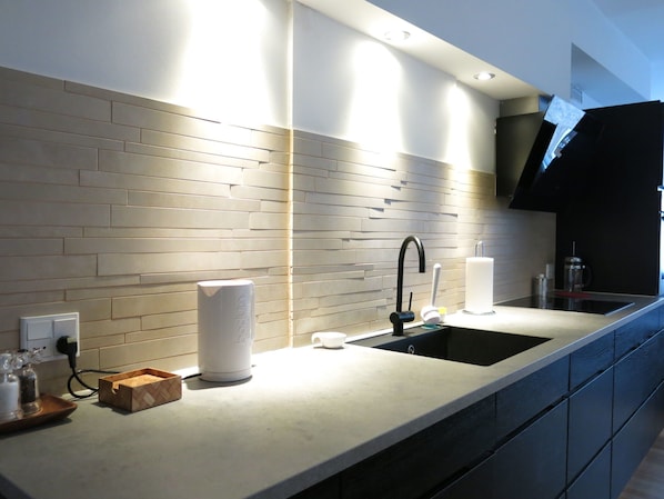 Modern kitchen with sink, black faucet, and light-colored tile backsplash.