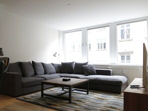 Relax in this stylish living room with a sofa, coffee table, and TV, offering a view of the city.