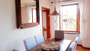 A dining area with a wooden table, blue chairs, a mirror, and a hanging light fixture. - HOUSE OF CHARACTER LAKE MAJOR  (Oggebbio)