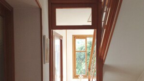 A narrow hallway with wooden doors and a window at the end leading to a room. - HOUSE OF CHARACTER LAKE MAJOR  (Oggebbio)