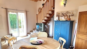 A dining area with a round wooden table and wicker chairs, a staircase, and a blue cabinet. - Brand new villa, fully equipped, 1.86 miles away from Palombaggia beach (Porto-Vecchio)