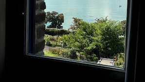 Una vista di un porto con diverse imbarcazioni, un muro di pietra e vegetazione sullo sfondo.