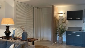 A modern living room with a sofa, a coffee table, a lamp, and a TV mounted on the wall.