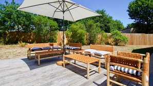 A wooden deck with outdoor furniture, including two sofas and a bench, under a large umbrella. - Cap-Ferret peninsula: Beautiful villa with heated pool (Lège-Cap-Ferret)