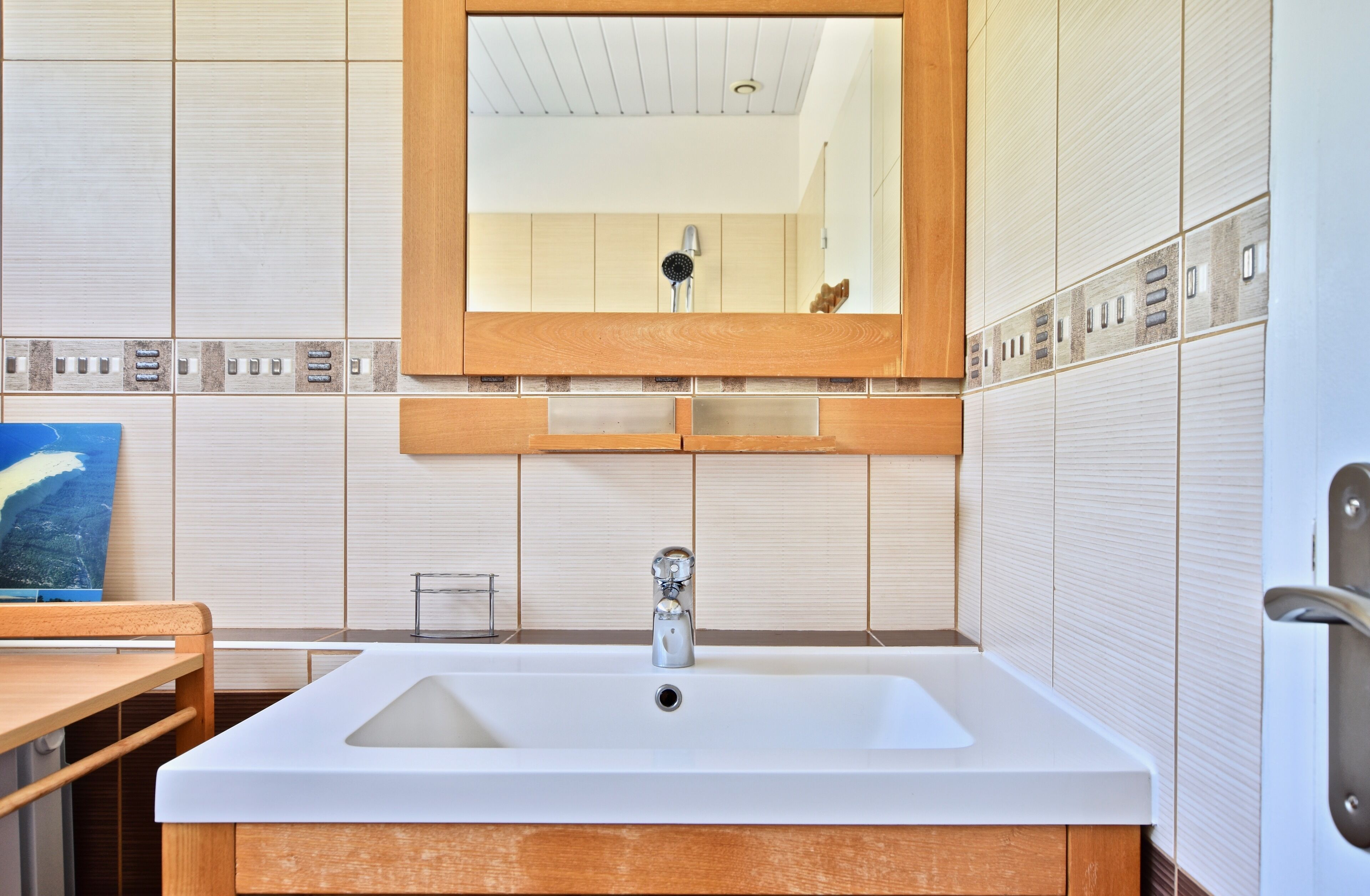 Ein Badezimmer mit Waschbecken, Holz-Badmöbeln und einem Spiegel darüber.