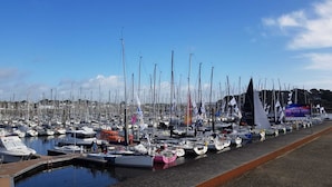 Ein Yachthafen mit zahlreichen angestaubten Booten, blauem Himmel und einem Kiesweg.