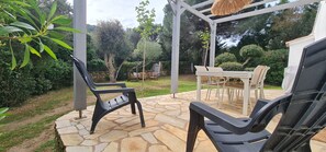 Eine Terrasse mit Steinplattenbelag, Gartenmöbeln und einer Pergola.