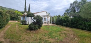 Ein Haus mit Garten, einer Pergola und einer Steinmauer.