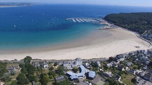 An aerial view of a coastal town with a sandy beach, a marina, and residential buildings.