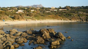 Eine Küstenlandschaft mit felsigen Ufern, einem Sandstrand und Gebäuden an einem Hügelhang.
