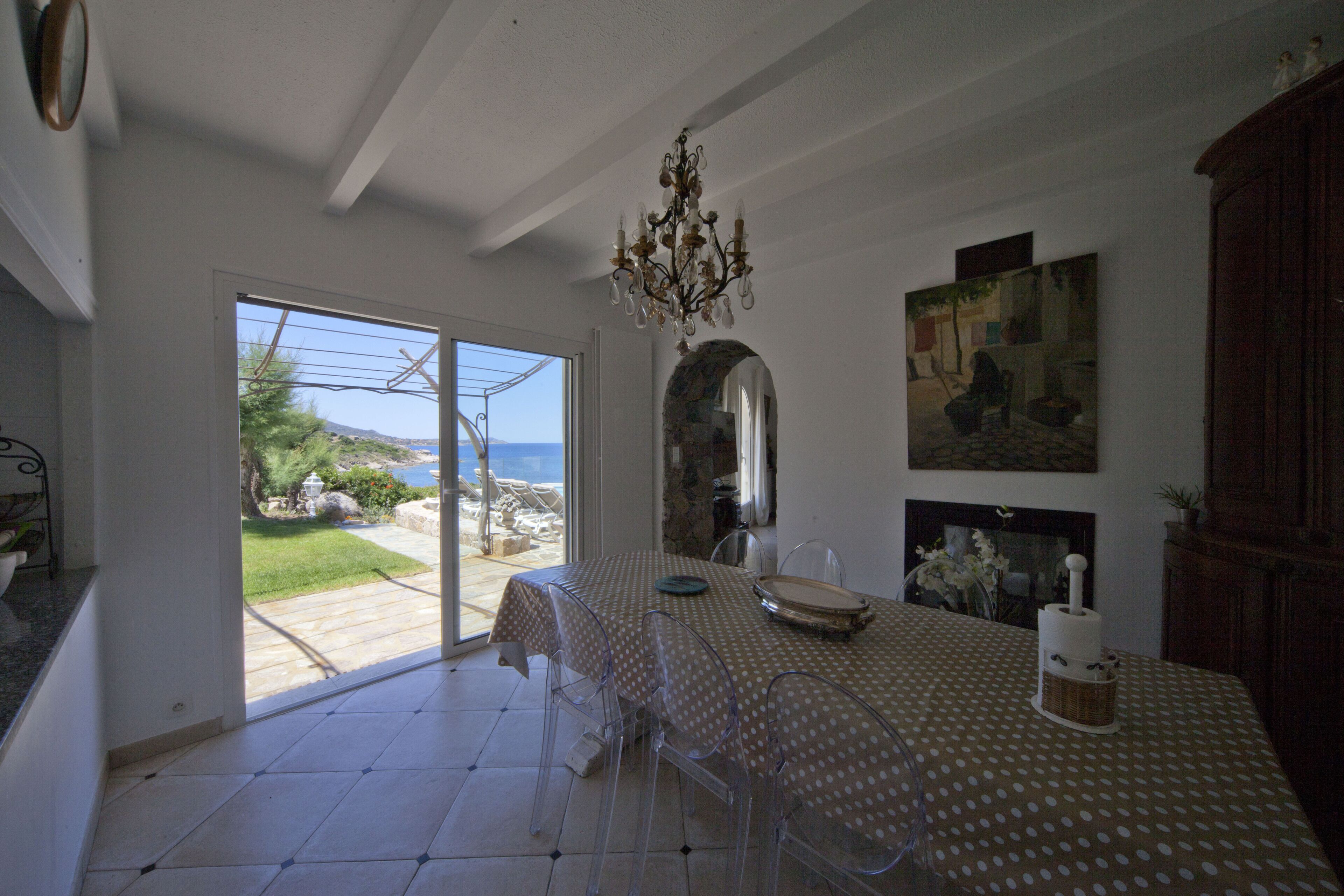 Un comedor con una mesa lista para dos, una araña y vistas al exterior.
