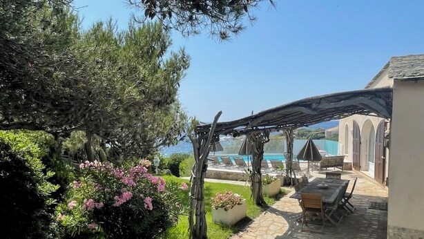 Eine Terrasse mit Pergola, Sitzgelegenheit und Blick auf einen Pool.