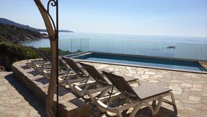 Ein Außenpool mit Liegestühlen und einer Terrasse mit Steinplatten.