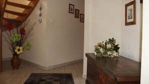 A hallway with a wooden ceiling, a vase with flowers, a wooden cabinet, and framed pictures on the wall. - Comfortable cottage prox. Obernai between Strasbourg and Colmar wine route (Stotzheim)