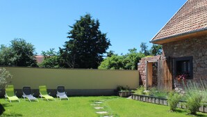 A stone house with a tiled roof, a stone wall, and a grassy yard with four green lawn chairs. - Comfortable cottage prox. Obernai between Strasbourg and Colmar wine route (Stotzheim)