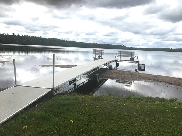 A lakeside dock with benches and a small boat. - Newer pet friendly lake home with 4 bedrooms and 3 baths (Manitowish Waters)
