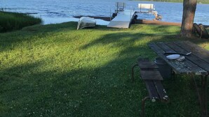 Un espace de pique-nique au bord du lac, équipé d’un quai pour bateaux, d’une pelouse et d’un banc en bois.