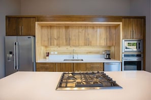 Una cocina moderna con armarios de madera, electrodomésticos de acero inoxidable y una isla central con estufa a gas.