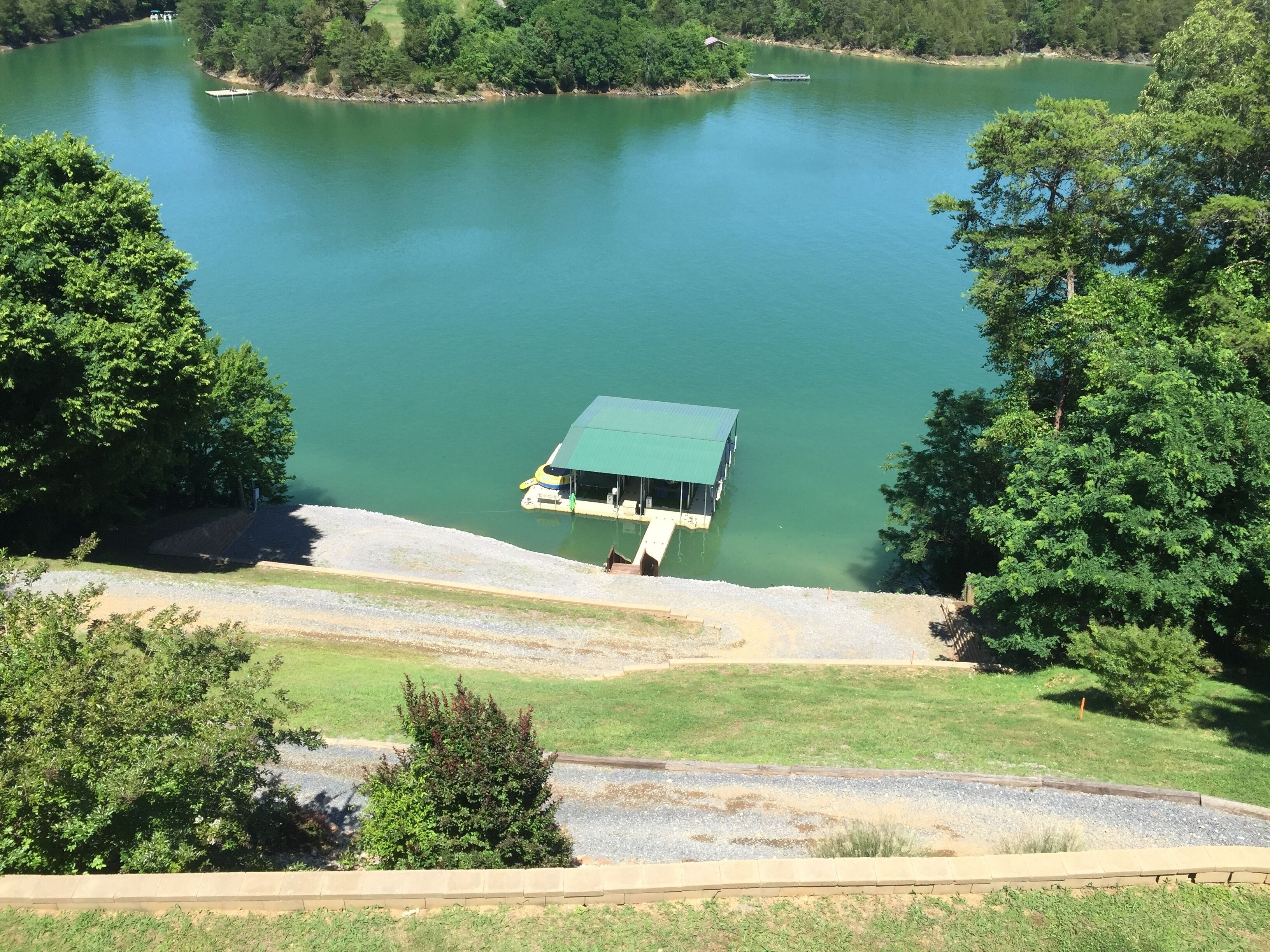A dock extending into a calm lake surrounded by dense trees.