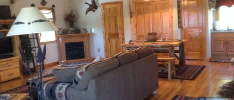 A cozy living room with a sofa, a lamp, a fireplace, and a dining area with a table and chairs.