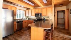 A modern kitchen with wooden cabinets, stainless steel appliances, and a large island with bar stools.
