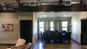 A spacious living room with a brown leather sofa, a patterned rug, and a dining area with a table and chairs.