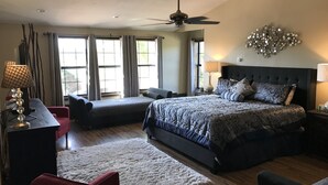 A bedroom with a large bed, two bedside tables, a ceiling fan, and a decorative wall piece.