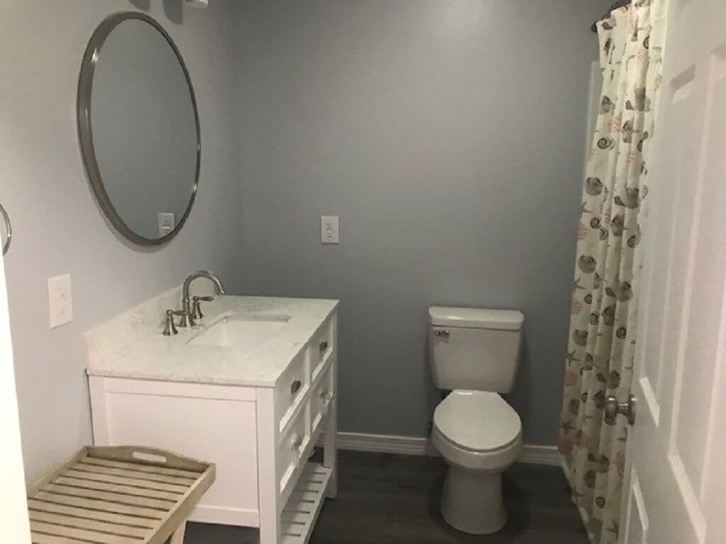 A small bathroom with a white sink, mirror, and toilet.