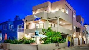A multi-story residential building with a 'ONE WAY' street sign, a 'P' street sign, and a 'SAN GABRIEL' street sign.
