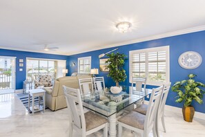 Relax in this open living space with a glass dining table, beige sofa, and white armchair.