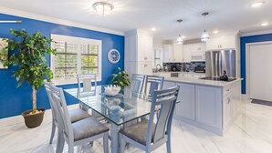Una cocina moderna con armarios blancos, una isla de vidrio y una pared de acento azul.
